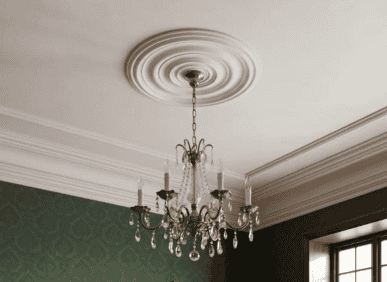 Chandelier hanging from decorative ceiling rose with intricate moulding details.